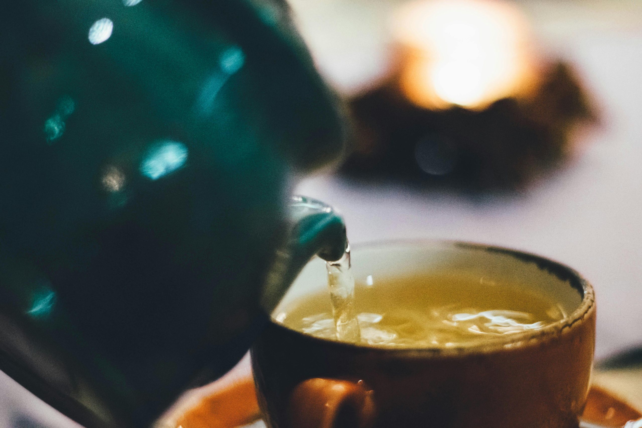 tea being poured from a teapot into a ceramic cup
