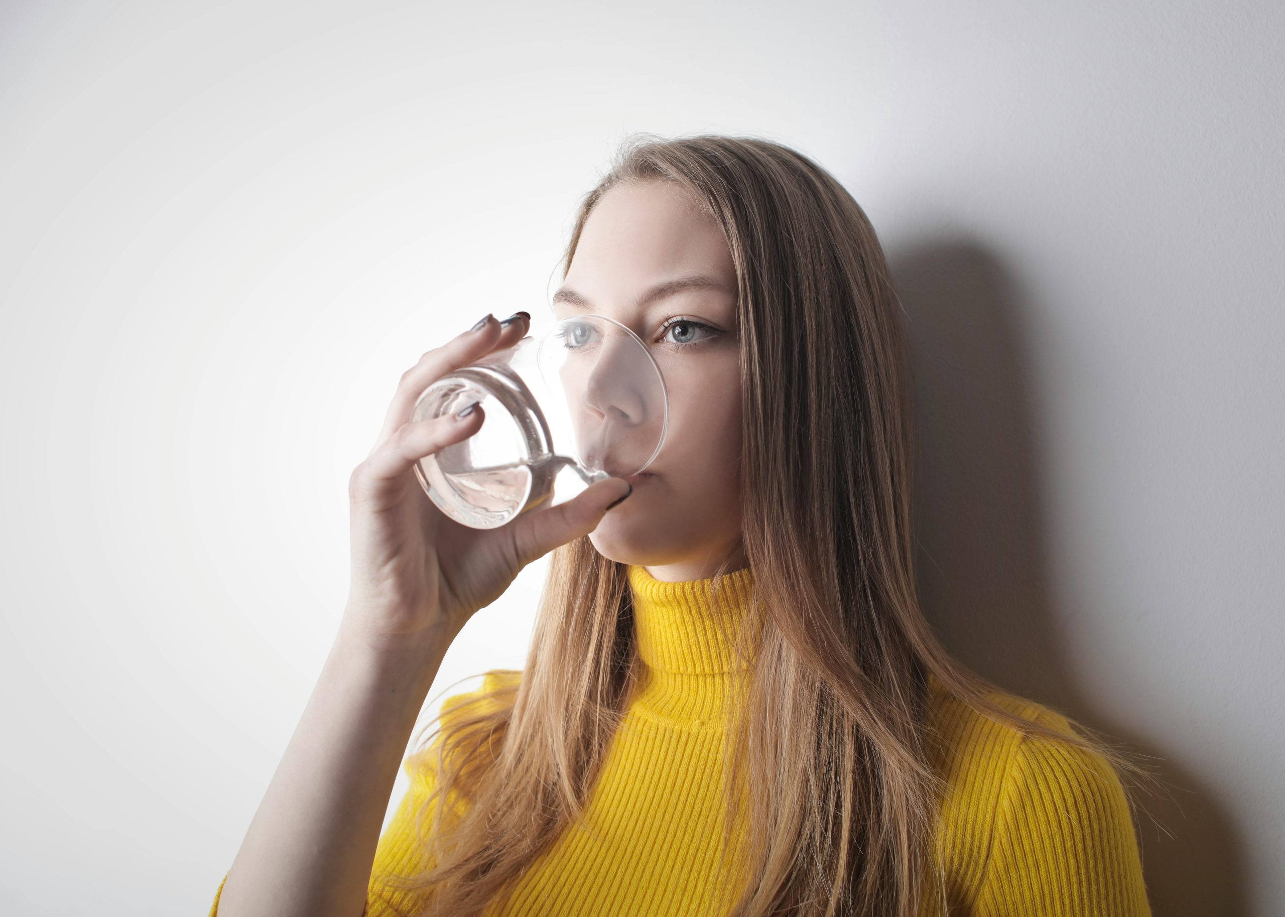 blonde woman drinking water from a glass